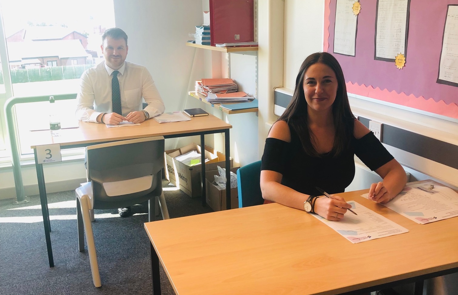 Adults smiling at school desks