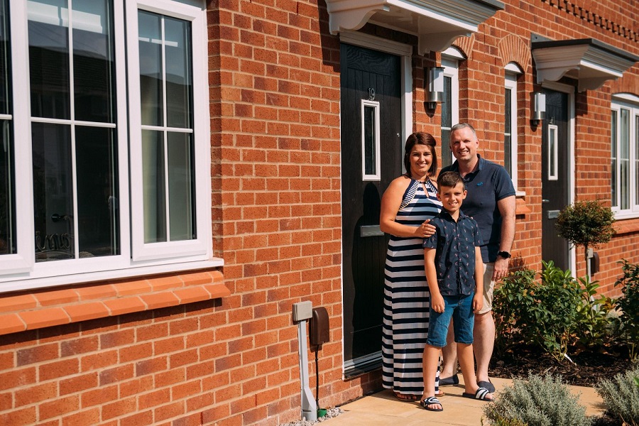 Mother, Father and Son smiling on doorstep of a house