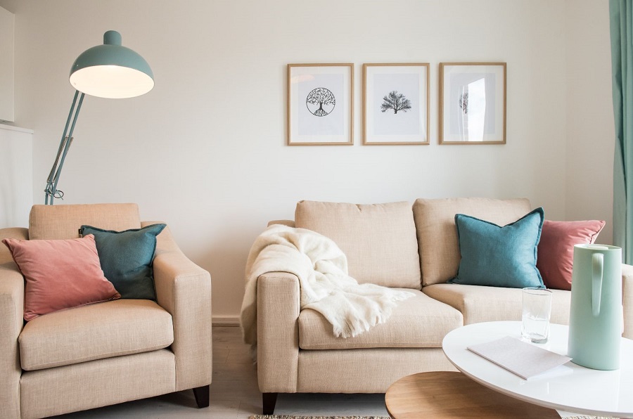 Beige sofa and armchair with pastel colours lamp and cushions