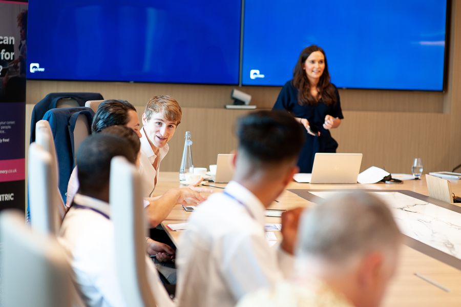 Young people are taught around a table with blue screen in background