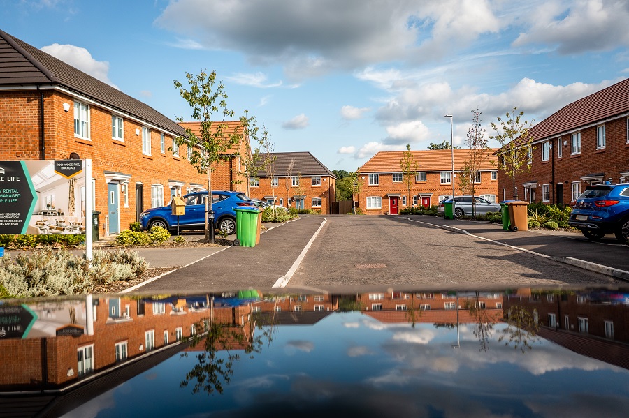 Artistic photograph of a residential road featuring houses and trees mirrored in the roof of a car