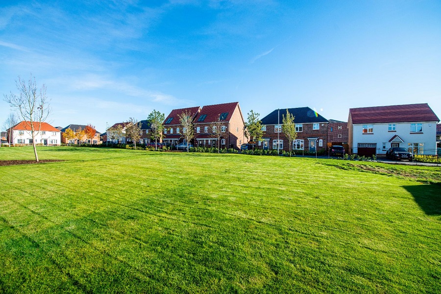 Different family houses across a green field at Hamilton Square, Atherton