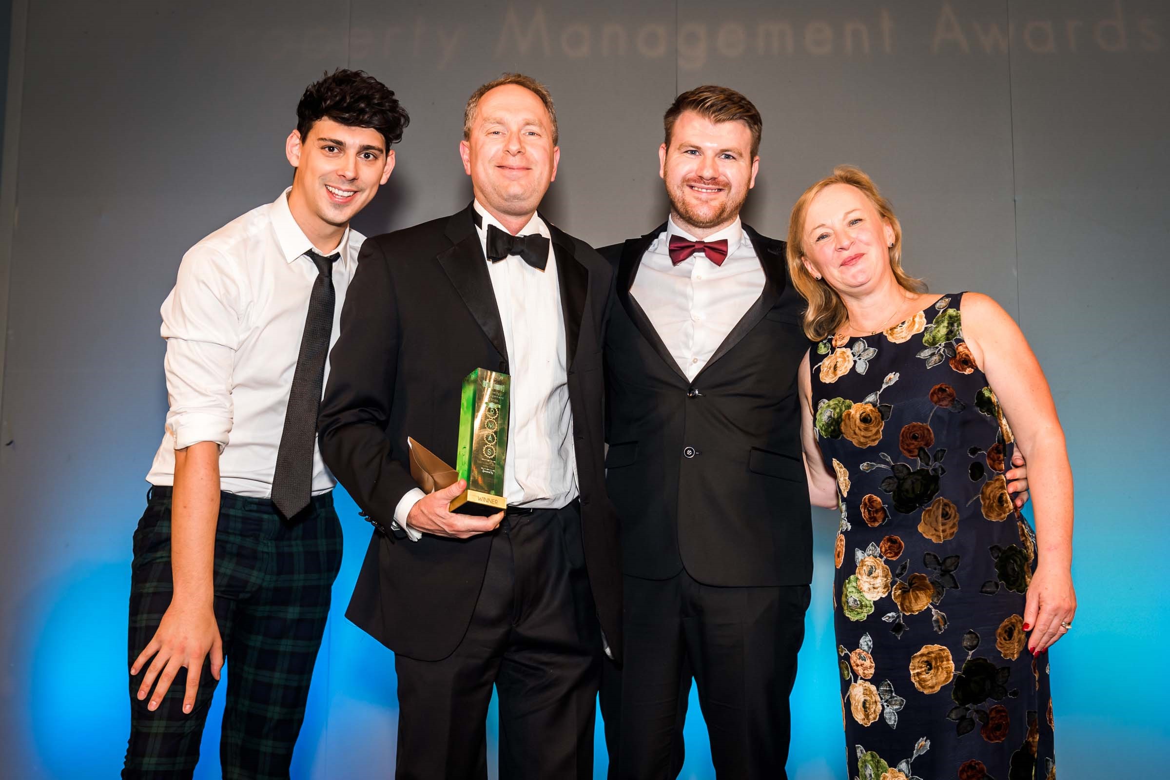 4 individuals taking picture after receiving management award