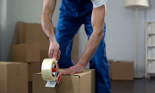 Moving company worker packing cardboard boxes, quality delivery services