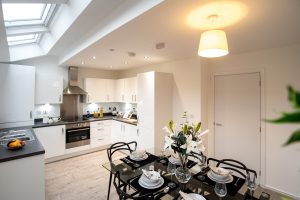 Open plan kitchen dining space with skylights, black table and pendant lamp