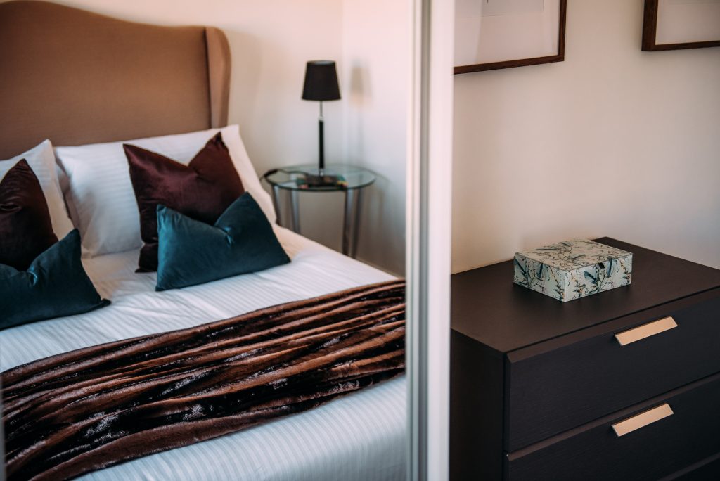 Bed reflected in mirrored wardrobe with velvet throw