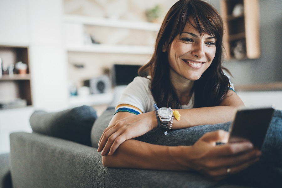 woman smiling at phone on the sofa