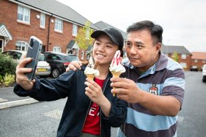 two men take a selfie with large ice creams