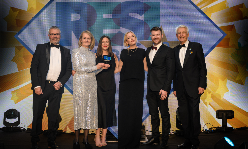 three men and three woman in black-tie attire posing with an award