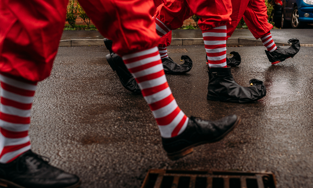 Three sets of legs walking in red and white striped tights