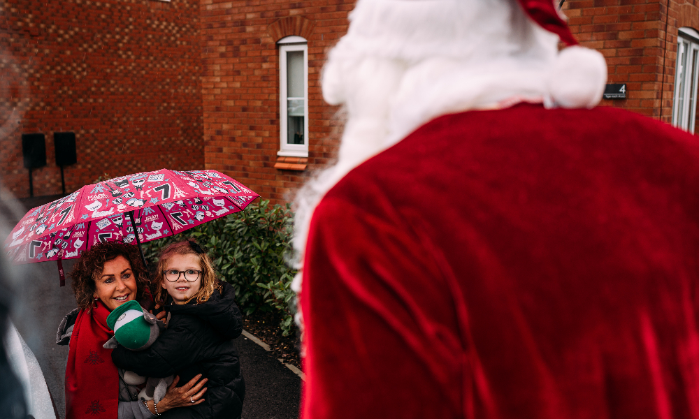 A woman and girl look up at Santa Claus