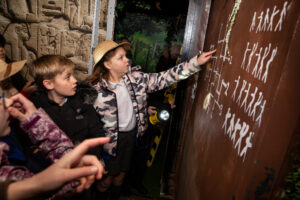 children in explorer hats tackle a riddle on a wall
