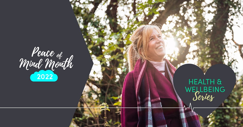 Woman in mauve coat smiling outside under trees