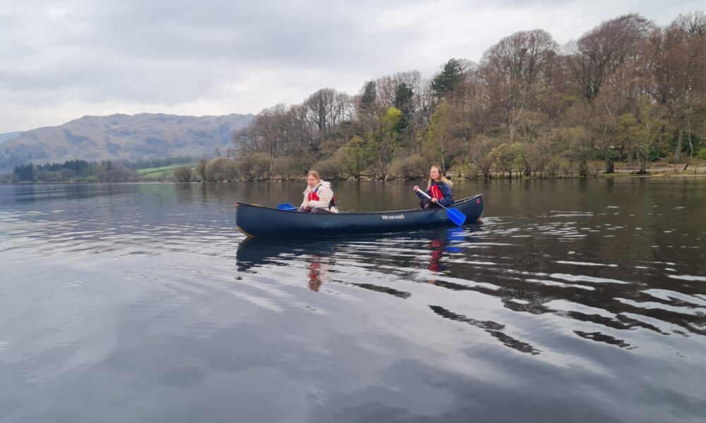 Two women paddle a boat on a lake