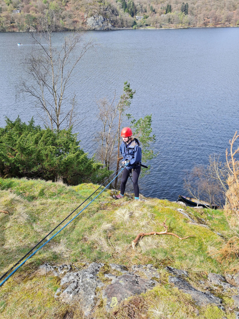 A girl abseils over a lake