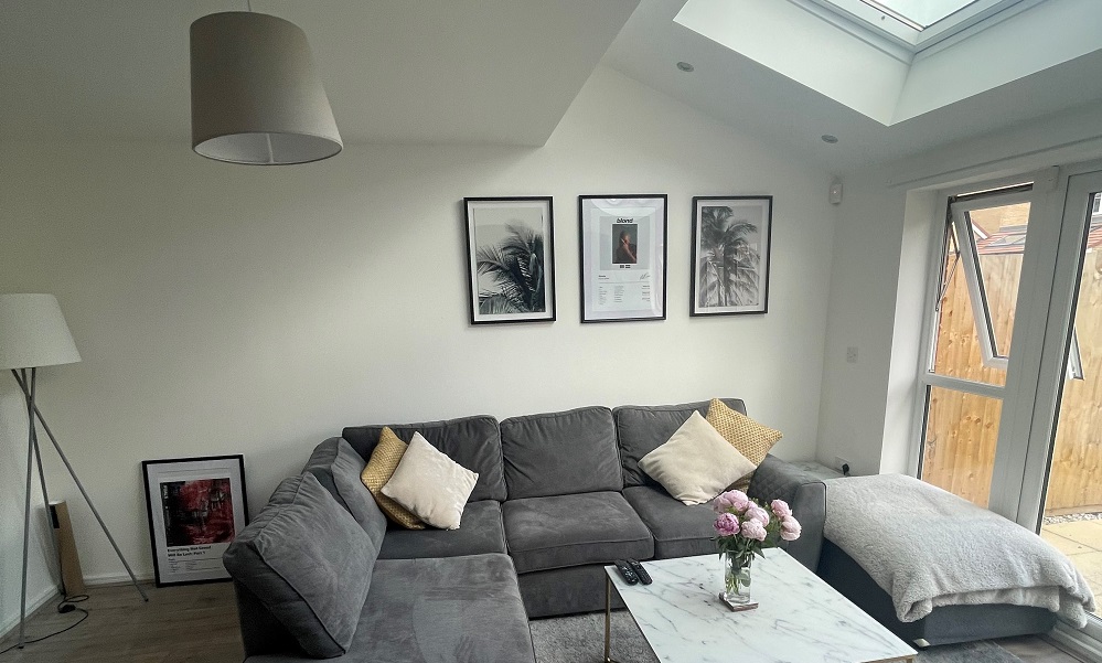 living room with vaulted ceiling and skylights, with a grey corner sofa