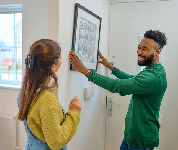 Couple hanging a picture in a new build rental home