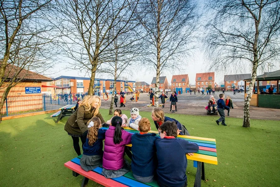 Children sat on colourful bench on school field
